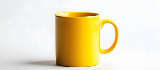 A bright yellow ceramic mug with a handle sits against a plain white background in a studio setting