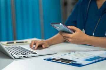 Fototapeta premium Medical Technology Concepts, The doctor is working on a smartphone and stethoscope and a digital laptop computer in a modern office in the morning at the desk.