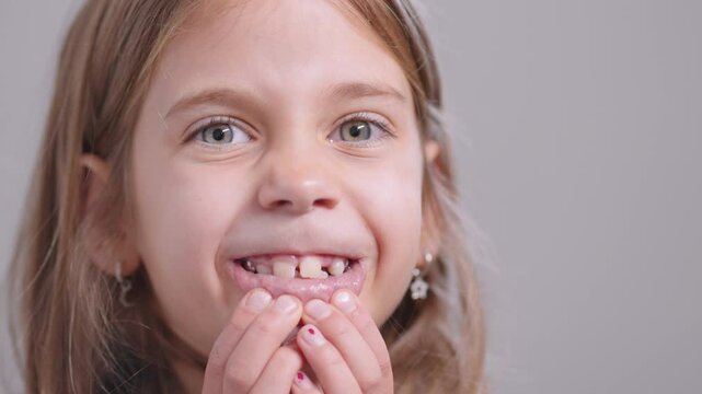 Playful girl stretching mouth wide to show teeth, making silly face with big smile, full of joy and innocence in cheerful childhood moment