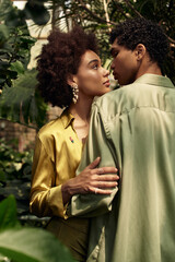 Fototapeta premium Young couple shares tender moment in lush greenhouse filled with vibrant greenery and plants