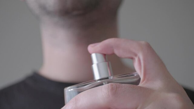 Close-up of man spraying perfume and deodorant on his skin