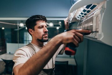 Skilled technician installs air conditioning unit in modern office space during the afternoon