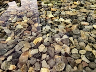 Smooth Riverbed Pebbles Under Clear Reflective Water