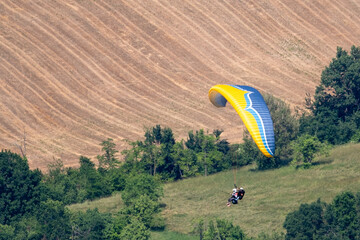 Sestola, Italy – 05 31 2025: Paraglider flies in the air. Aerial view of paragliding. Paraglider flies above the mountains in a bright sunny day. Concept of extreme sport.
