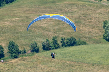 Sestola, Italy – 05 31 2025: Paraglider flies in the air. Aerial view of paragliding. Paraglider flies above the mountains in a bright sunny day. Concept of extreme sport.
