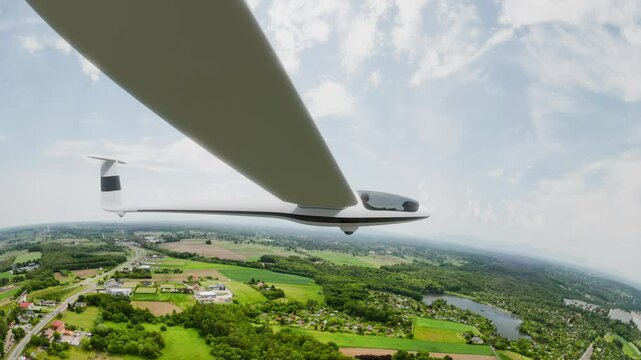 A sleek, white glider soars gracefully over a picturesque landscape beneath a vibrant sky.