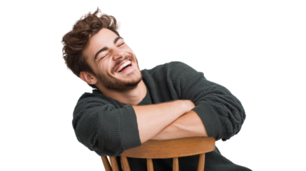 A cheerful young man laughing while seated on a wooden chair, exuding joy and warmth.