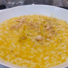 Risotto with pumpkin, rosemary, biscuits,  cheese in a white plate on the table, close-up. Italian cuisine