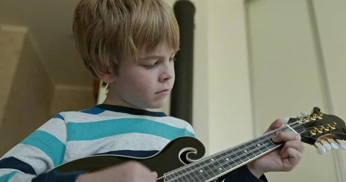 Caucasian Kid Play Mandolin at Home. European Boy Practice Music 4K 10-bit