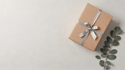 A brown box with a silver ribbon on top of a white background. The box is wrapped in a ribbon and is placed on a table