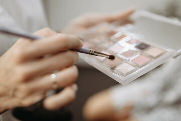 Make-up artist at work. Make-up artist tools brush and palette for make-up in hands of specialist