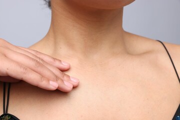 Young woman with healthy skin on light grey background, closeup