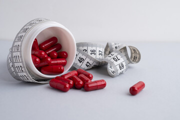 Measuring tape and tablets, vitamins on a light background with space for text. Concept of losing weight, dieting, burning fat, healthy eating.  