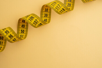 Yellow measuring tape on a yellow background. Tool for measuring length and volume. Tape for measuring in the clothing industry or the volume of the human body