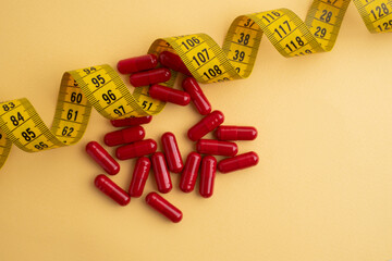 Measuring tape and tablets, vitamins on a light background with space for text. Concept of losing...