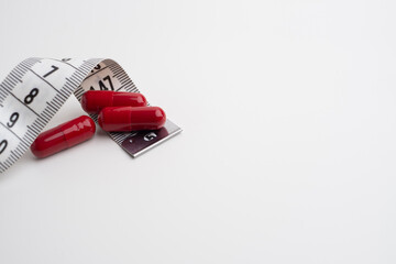 Measuring tape and tablets, vitamins on a light background with space for text. Concept of losing weight, dieting, burning fat, healthy eating.  