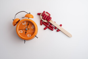 Time to take pills. Alarm clock shows time to take medicine. Taking vitamins or medicine. Concept of health care, medicine, pharmacy, disease prevention