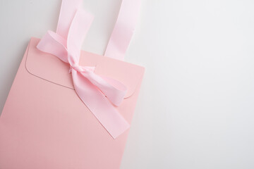 Pink box with pink ribbon on white background. Space for text and logo. Gift wrapping