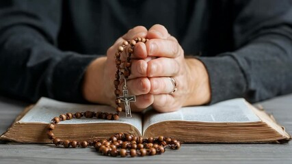 Hands holding rosary in prayer over open book on wooden table symbolizing faith and devotion in religion - Powered by Adobe