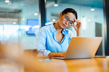 Focused young woman working on a laptop in an office environment