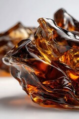 Close-up of glossy, amber-colored glass art with intricate, flowing textures and abstract shapes.
