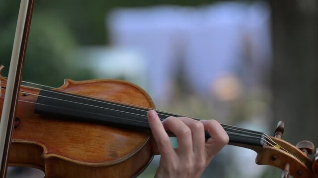 Musician violinist performing classical music, fingers expertly moving across strings during live concert with dramatic slow motion closeup capturing artistic skill