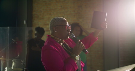 Woman holding the Bible and addressing the congregation from a stage, leading a spiritual gathering in a church with heartfelt faith and devotion