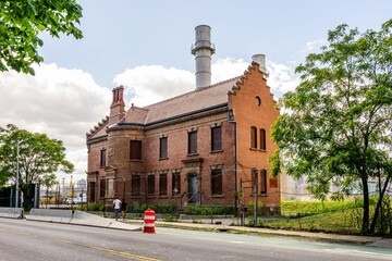 Fototapeta premium Historic red brick building with chimney and trees.