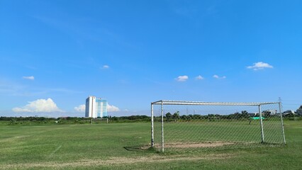 Soccer Field with Distant Skyscraper Under Blue Sky