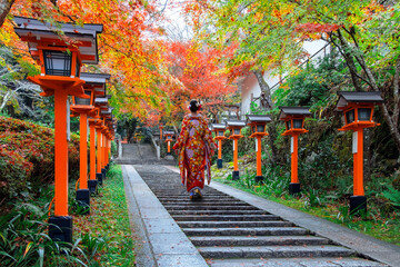 Japanese Woman in Traditional Kimono Dress at Kuramadera in a beautiful autumn scenery in Kyoto, Japan is a large temple complex spread across the side of Mt. Kurama
