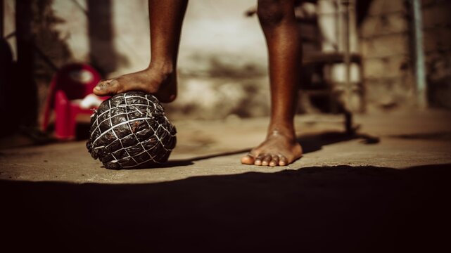 Child's foot on a handmade soccer ball outdoors.