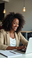 African american woman with a bright smile is focused on her laptop in a modern office setting, showcasing a positive work environment during the day.