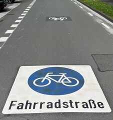 Fahrradspur, blau weißes Hinweiszeichen auf dem Boden, dass die Straßen eine Fahrradstraße ist