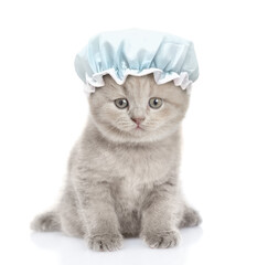 Cute kitten with tiny shower cap on it head sits in front view and looks at camera. isolated on white background