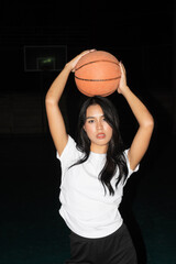 Young beautiful woman in basketball court during night