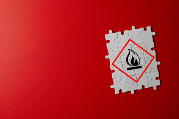 White puzzle pieces forming a flammable warning sign on red background.,Symbolizes risks, danger alerts for combustible substances,chemical warnings, workplace precautions,attention sign industrail.