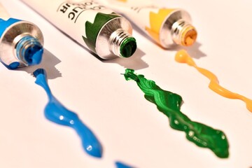 Open acrylic paint tubes with colorful paint spilled around. Creative mess full of vivid color and inspiration.

