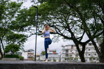 A woman is doing a yoga pose in a park
