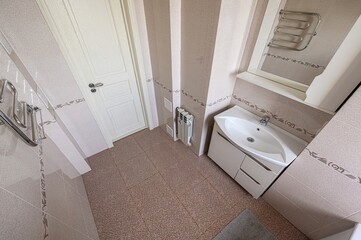 Neutral bathroom with tile walls, white door, vanity, and heated towel rack. Clean and simple design