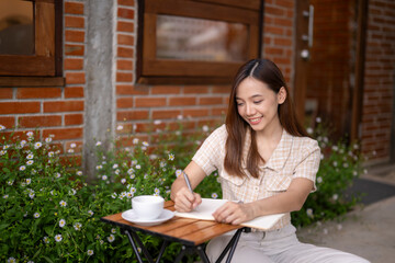A woman is sitting at a table with a notebook and a cup of coffee