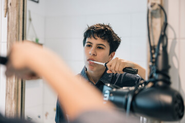 Teenager girl brushing teeth in bathroom mirror during morning routine