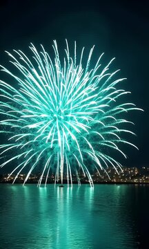Teal Fireworks Exploding over a Calm Body of Water Reflecting City Lights at Night Creating a Festive Atmosphere for Adobe Stock
