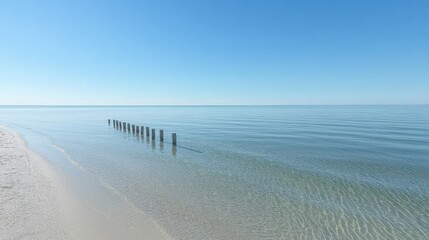 Clear Blue Seascape with Wooden Pilings on a Sandy Beach Under Bright Sky