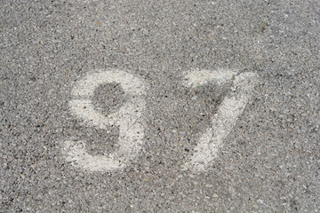 An aerial view shows the number 97 painted in white on a textured asphalt surface