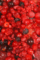 A close-up view of a vibrant mix of frozen red berries, including cranberries, raspberries, and blackberries, showing their frosty texture