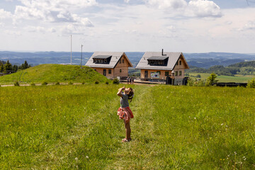 Girl enjoying the view on a summer meadow near mountain cottages, countryside in Czechia