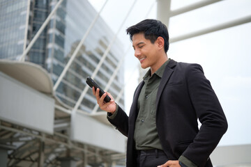 Confident businessman in a suit checking phone messages in a modern cityscape.