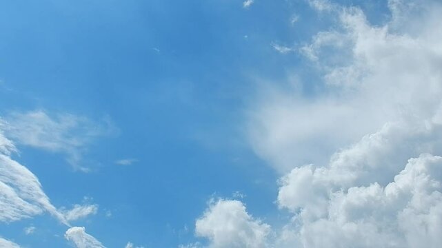 Natural blue sky background with slowly moving white clouds Cumulus. Topics: heaven, cloudscape,  meteorology, weather, climate, beauty of nature, air space