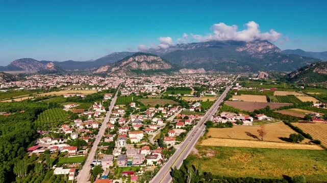 Drone capturing the beauty of Ortaca, with its green forest, houses, and mountains under a clear blue sky in Mugla, Turkiye