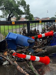 Flood debris against a guardrail after wind and  flood waters. Damage from a flooding event in a residential neighborhood after severe rains. Insurance claim aftermath from flood damaged areas.